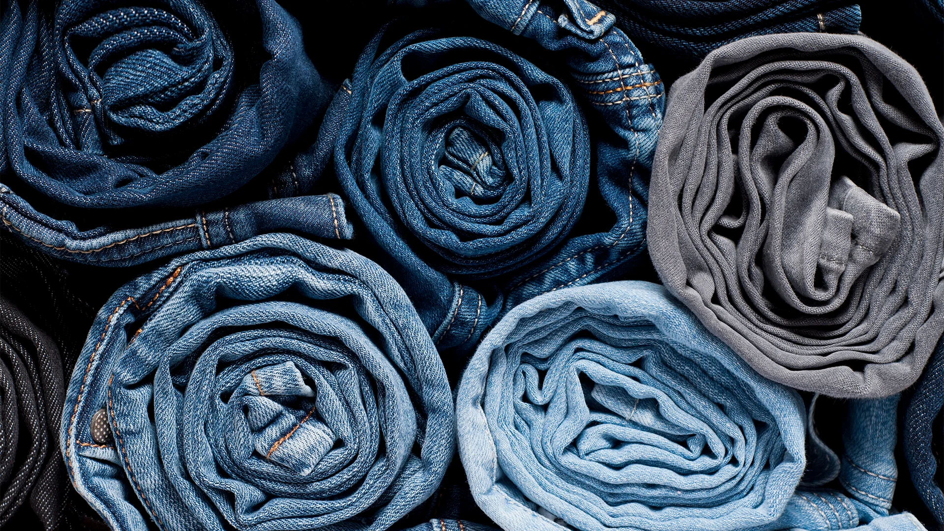 Verschiedenfarbige Jeans zusammengerollt aufeinander (Foto)