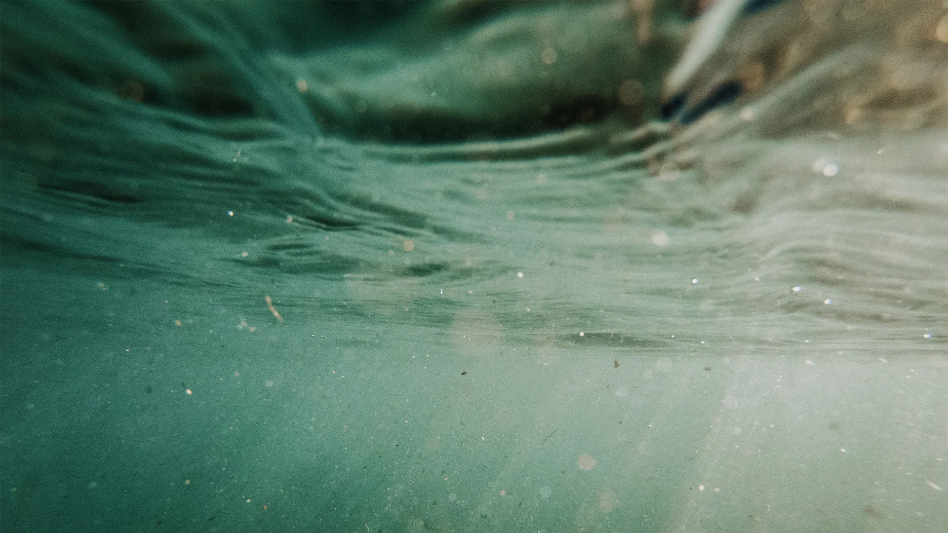 Türkisblaues Meerwasser mit sichtbaren Microplastik-Partikel (Foto)